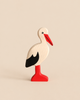 A Holztiger Stork handcrafted wooden toy featuring a red beak and legs with black wing detail.