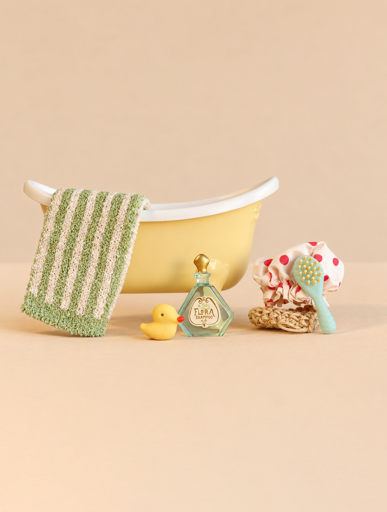 A miniature yellow Maileg Bathtub Set featuring a striped towel, a rubber duck, a bottle of shampoo, a shower cap, and a brush.