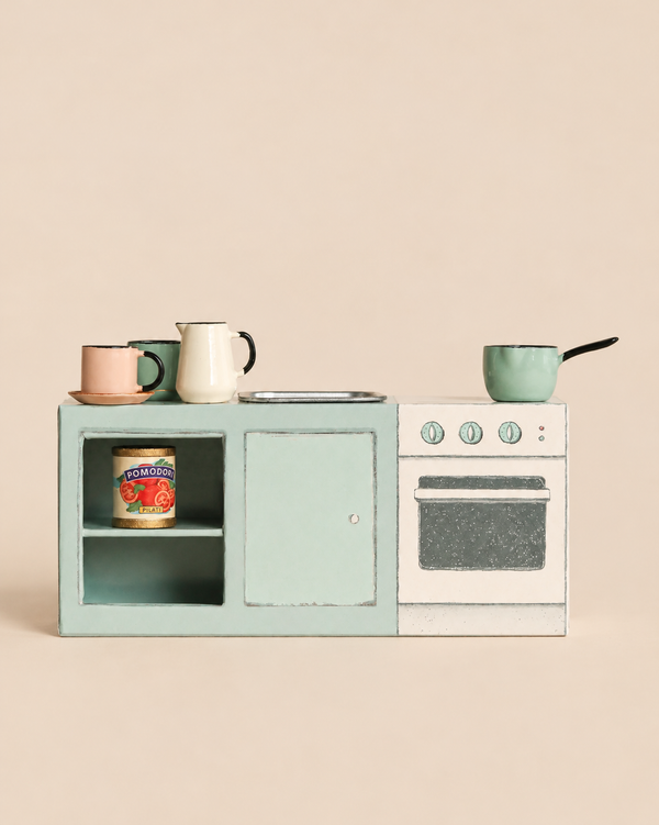A Maileg Kitchen Counter, Mouse Size, featuring a stove, sink, and open shelving holding a toy can of tomatoes, mugs, and a saucepan.