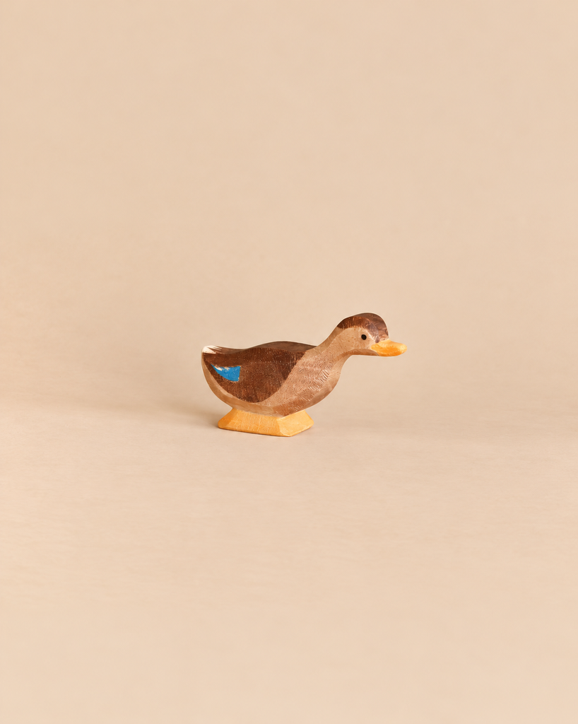 Ostheimer Long Neck Duck handcrafted wooden toy with a brown body, yellow beak and feet, and a blue patch on its wing, perfect for imaginative play.