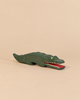 An Ostheimer Crocodile handcrafted wooden toy with a green body, yellow eye, and open red mouth showing white teeth, perfect for imaginative play.