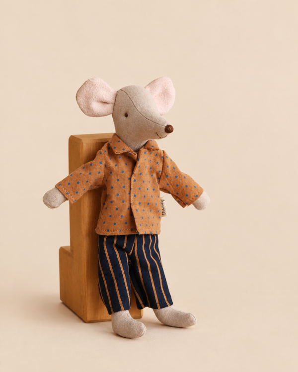 Maileg Dad Mouse With Extra Outfit wearing a brown shirt with blue polka dots and dark pinstriped trousers, standing next to a small wooden block.