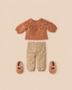 Maileg Pants and Knitted Sweater, Size 3, featuring a terracotta-colored knitted sweater with a lace pattern, flower-printed pants, and two pink mary jane shoes arranged on a plain background.