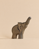 A sustainable wooden Handmade Holzwald Baby Elephant figurine with its trunk raised, perfect for imaginative play.