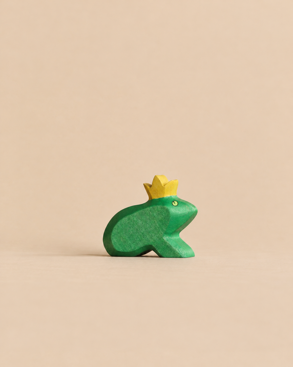 A small green Handmade Holzwald Frog King figurine crafted from wood and wearing a yellow crown.