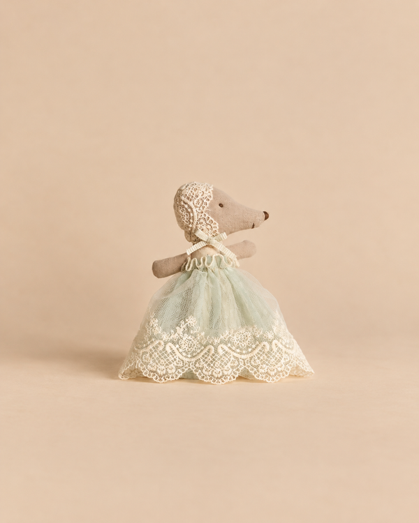 A Maileg Baby Mouse in Gown - Mint, a stuffed baby mouse wearing a lace bonnet and a mint green tulle celebration dress with lace trim.