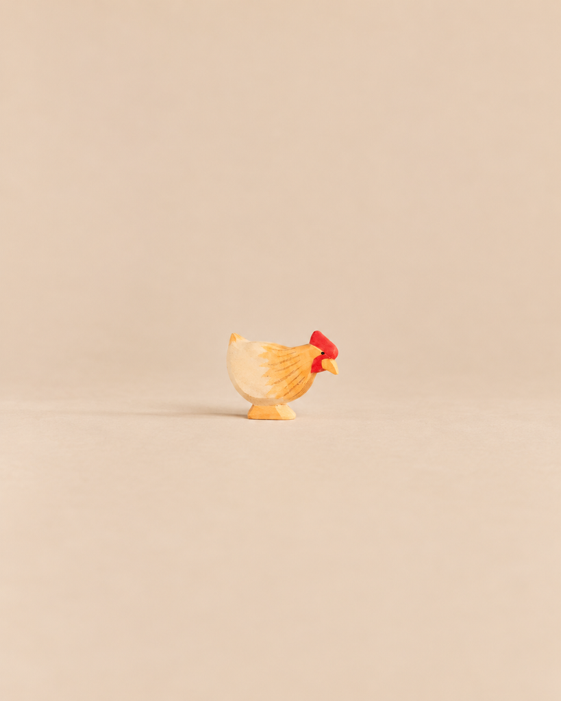 Ostheimer Hen Standing - Ochre, a handcrafted wooden hen figurine with yellow and ochre plumage and a red comb.