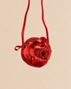 Konges Sloejd Rose Shoulder Bag, a round, red, glittery bag with a slim shoulder strap and zipper closure.
