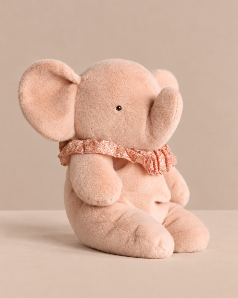 A soft pink Maileg Elephant Plush, Big - Powder sitting upright, wearing a ruffled lace collar as a charming stuffed animal.