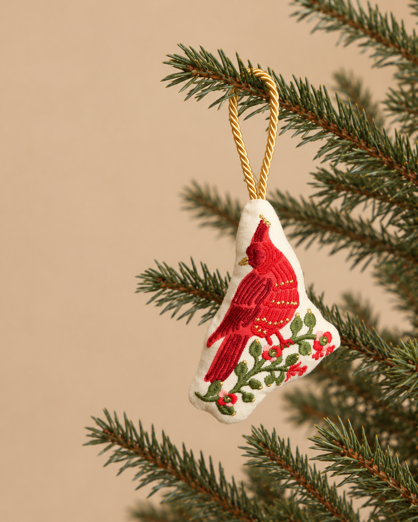 Cardinals Embroidered Ornament featuring a plush cotton cardinal perched on a branch with holly berries, hanging from a pine branch by a gold cord.