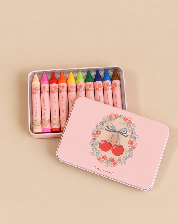 A set of ten multicolored Konges Sloejd Beeswax Crayons - Cherry Bow in a light pink metal tin, with the lid featuring an illustration of cherries and a floral wreath.