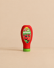 An Erzi Ketchup Pretend Food wooden bottle with a green cap and a label featuring tomatoes.