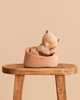 A Maileg Small Sleeping Kitten in Basket resting in a small fabric basket placed on a wooden stool.