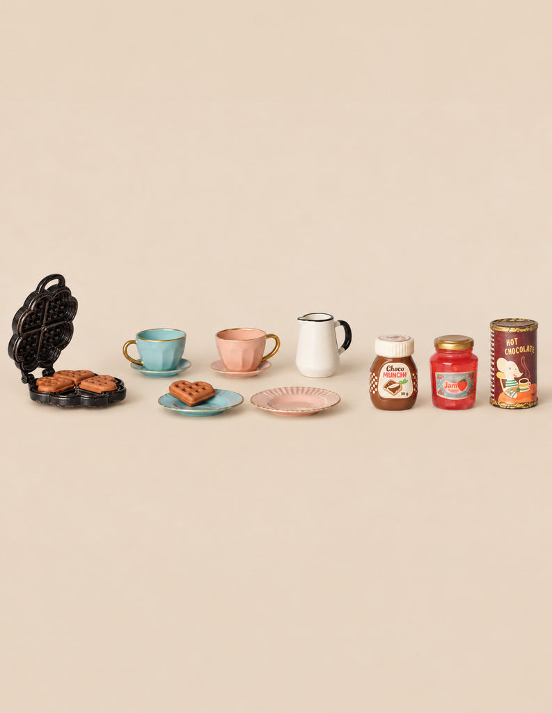 The Maileg Breakfast Table Set includes a heart-shaped waffle iron, two teacups with saucers, a creamer, and jars of chocolate spread, jam, and hot chocolate.