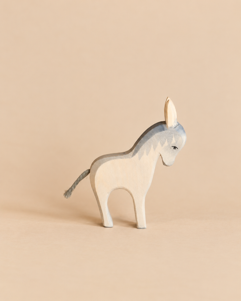 An Ostheimer Donkey - Standing, a handcrafted wooden toy shown in profile with a grey mane and a short cord tail, perfect for imaginative play.