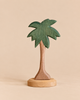 Ostheimer Tree - Palm with Stand, Leaves Up, a handcrafted wooden palm tree toy featuring a green leafy top and a brown trunk on a round base.