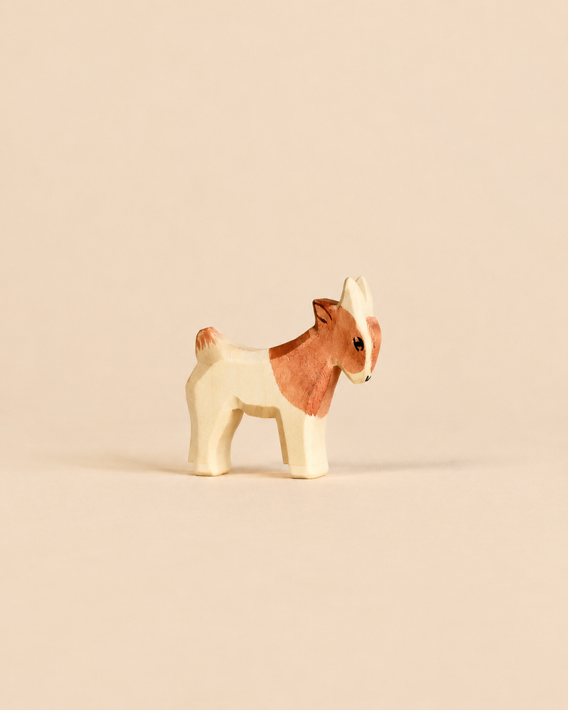 A small, handcrafted Ostheimer Goat Kid - Standing, depicted in profile with brown patches.