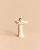 Maileg Bathroom Sink, Mouse Size - Off White, featuring a miniature white pedestal design with a gold-colored faucet, created as a charming mouse house accessory.