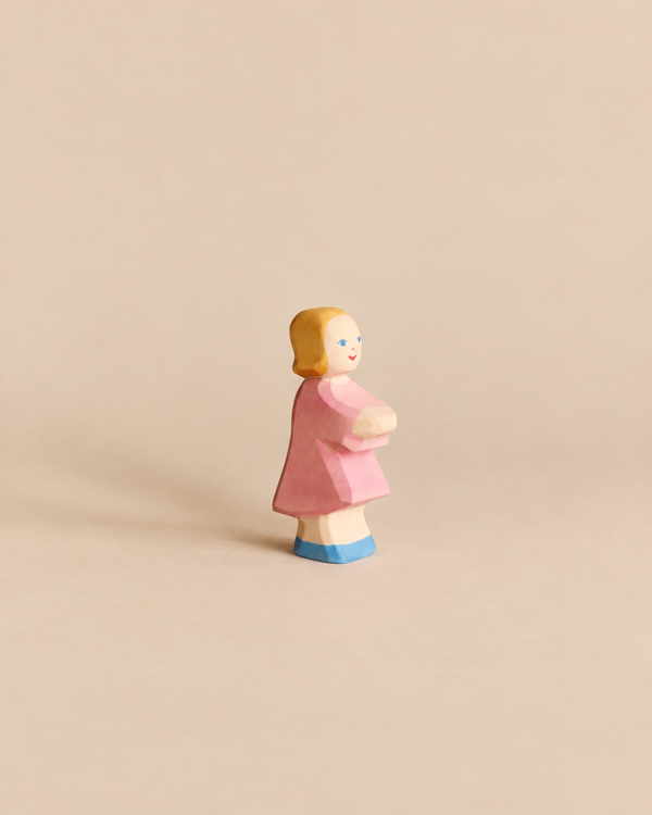 Handcrafted Ostheimer Daughter in Pink Dress wooden figurine of a girl with blonde hair, a pink dress, and blue shoes.