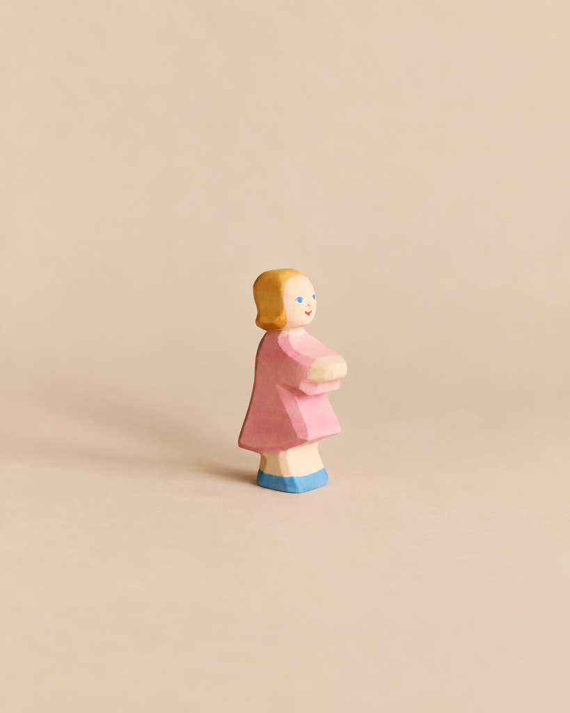 Handcrafted Ostheimer Daughter in Pink Dress wooden figurine of a girl with blonde hair, a pink dress, and blue shoes.