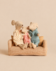 Maileg Family Set of mum, dad, and baby mice in fabric clothing sitting together on a miniature plaid sofa.