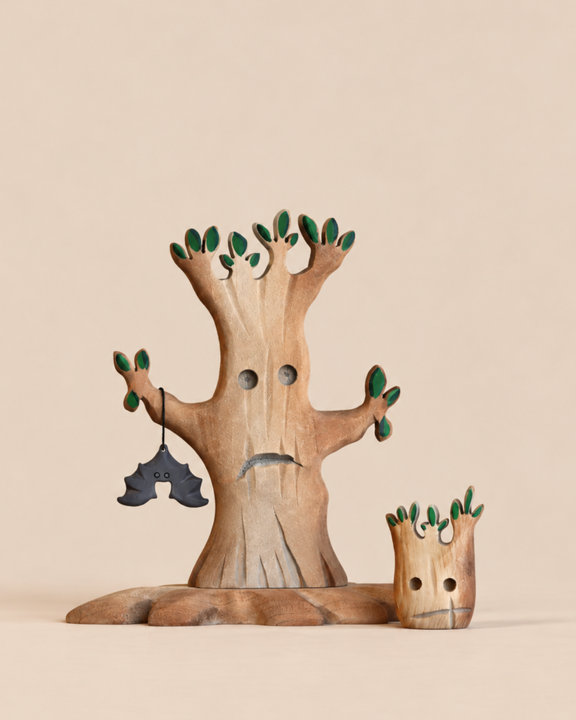 The Handmade Bumbu Haunted Tree Halloween Set features a large tree with a sad face holding a black bat ornament and a smaller tree stump with a sad face, all crafted from wood.