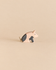 Ostheimer Spotted Piglet - Sitting, a handcrafted wooden toy in a sitting position with black patches and a simple twine tail, perfect for imaginative play.
