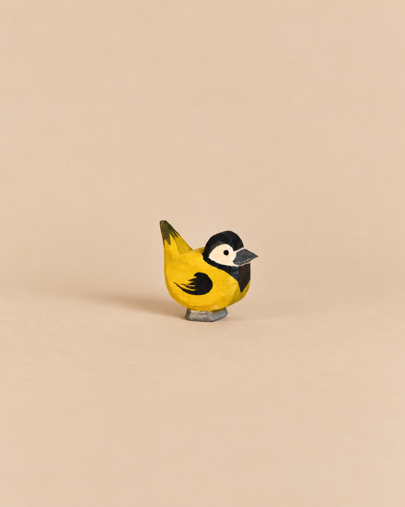 Handcrafted wooden Ostheimer Bird - Goldfinch with a yellow breast, black head markings, and white cheek patches.