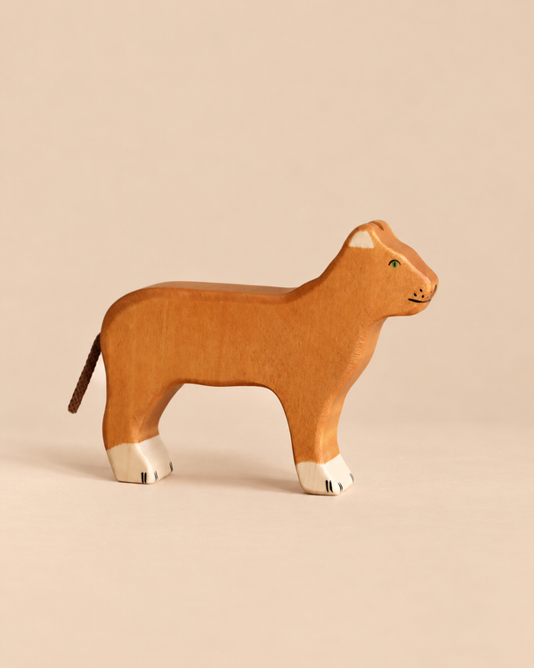 Handcrafted Holztiger Lioness wooden toy with a tan body, white-tipped paws, and a cord tail.