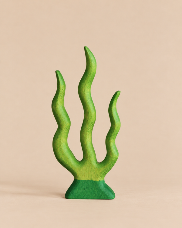 A sustainable Handmade Holzwald Seaweed wooden toy shaped like a three-pronged piece of green seaweed.
