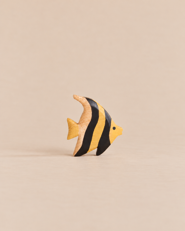 A small, wooden Handmade Holzwald Moorish Idol Fish toy featuring yellow and black vertical stripes.