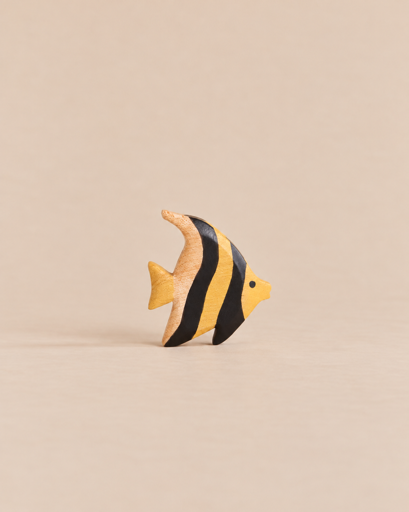 A small, wooden Handmade Holzwald Moorish Idol Fish toy featuring yellow and black vertical stripes.