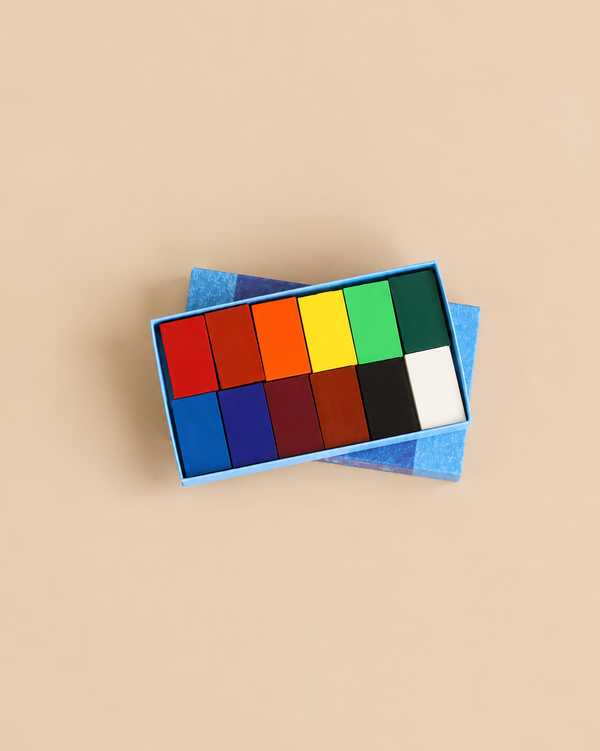 Stockmar Wax Block Crayons Box -12 Assorted featuring twelve rectangular wax blocks in assorted colors, arranged in two rows within an open blue box.