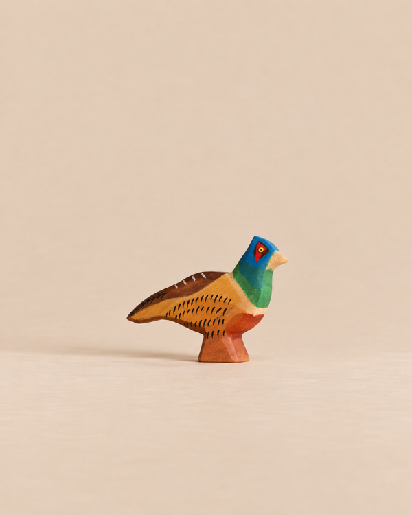 Handmade Holzwald Bird - Pheasant, a small, hand-painted wooden toy with a blue head, green neck, and brown and yellow body.
