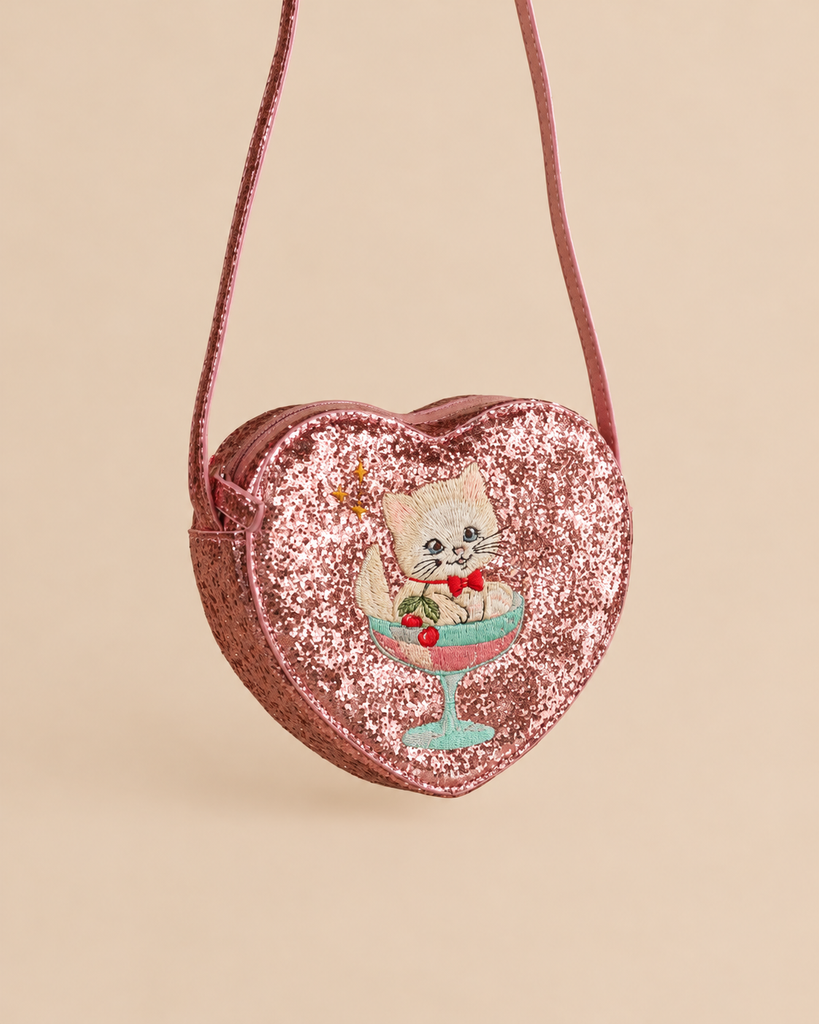 Konges Sloejd Tut Kitty Shoulder Bag, a pink heart-shaped glitter bag featuring an embroidered kitten sitting inside a cocktail glass.