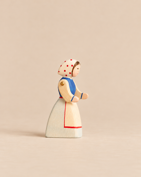 Ostheimer Farm Wife handcrafted wooden figurine of a woman wearing a blue bodice, a white apron with red trim, and a red-polka-dot headscarf.