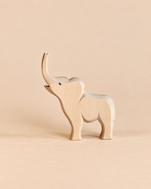 An Ostheimer Small Elephant - Trumpeting, a handcrafted wooden figurine with its trunk raised, designed for imaginative play.