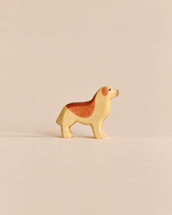 A small wooden Handmade Holzwald Dog - Golden Retriever figurine with light tan and brown markings standing in profile, representative of sustainable toys.
