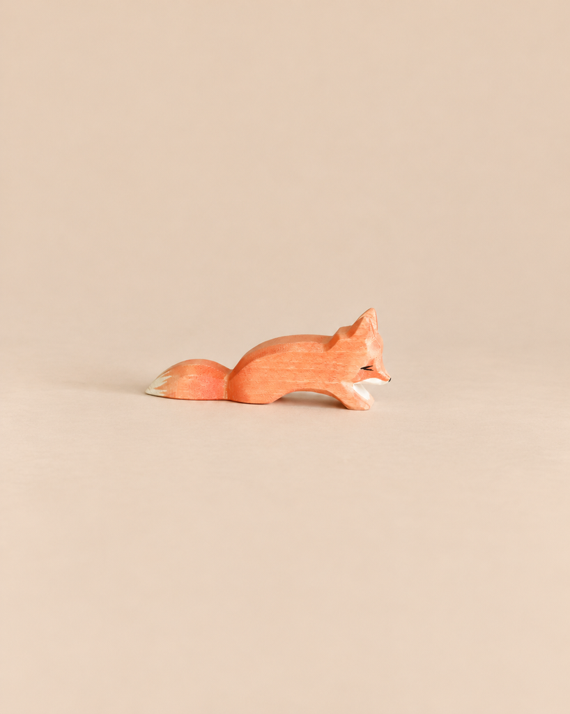 An Ostheimer Small Fox - Creeping, a small, handcrafted wooden fox figurine in a crouching position, perfect for imaginative play.