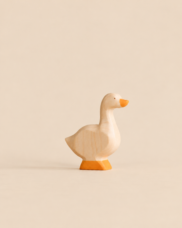 A Handmade Holzwald Goose, a small wooden toy for imaginative play with a painted orange beak and feet.