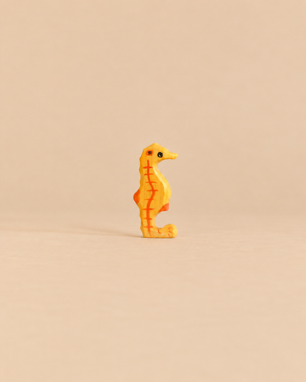 Holztiger Seahorse, a handcrafted wooden toy in yellow with orange stripes.