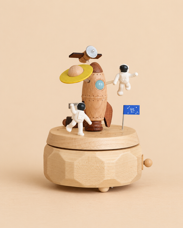 A Wooden Spaceship Music Box featuring a rocket, two small astronaut figures, and a blue flag on a faceted wooden base.