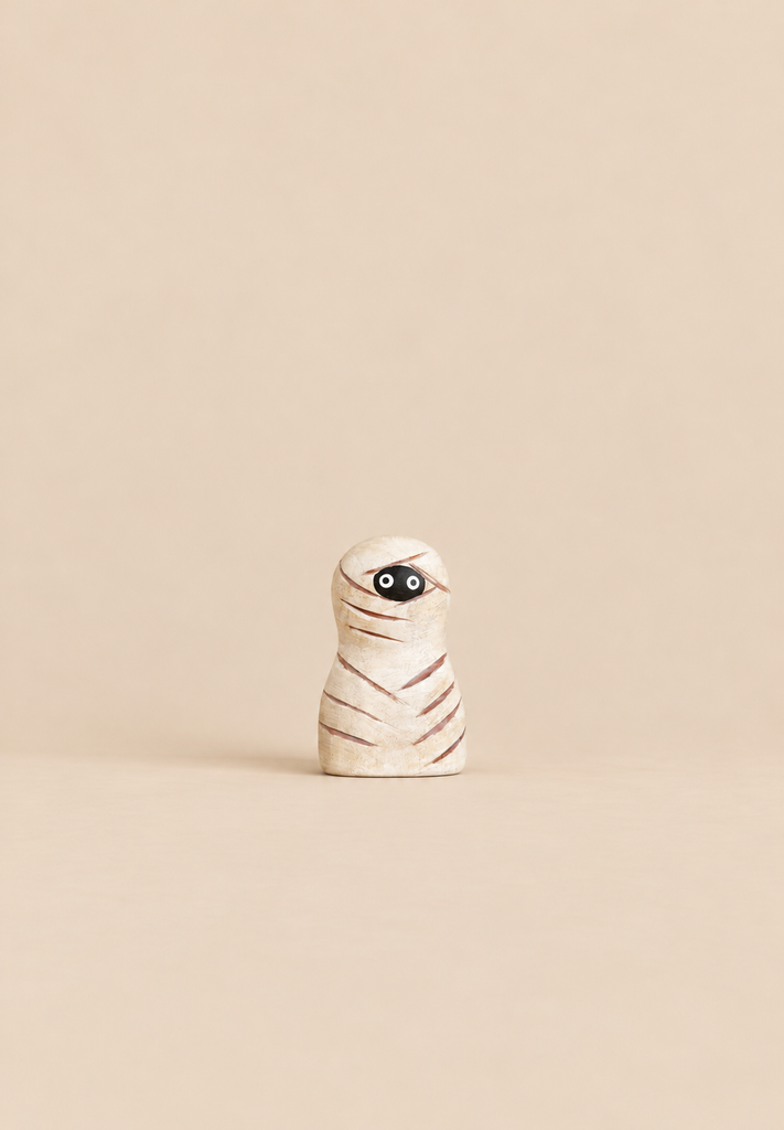 Small wooden mummy figurine from the Handmade Bumbu Haunted Tree Halloween Set, featuring carved wrappings and two black eyes.
