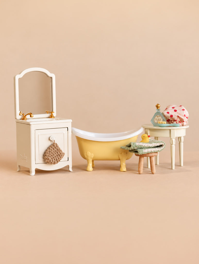 Maileg Bathtub Set featuring a sink dresser with a mirror, a yellow clawfoot tub, a small stool with a rubber duck, and a side table with bathing accessories.