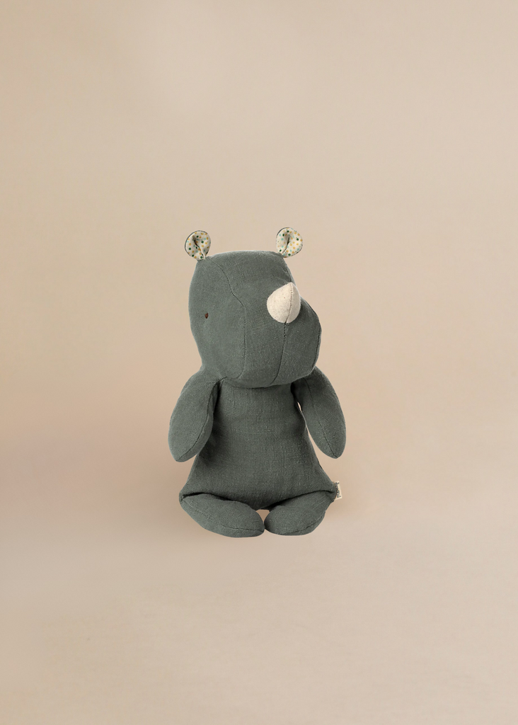 The Maileg Small Rhino - Pine is a gray stuffed animal with a white horn, floral inner ears, and a minimalist design made from soft fabric, shown sitting against a plain beige background.