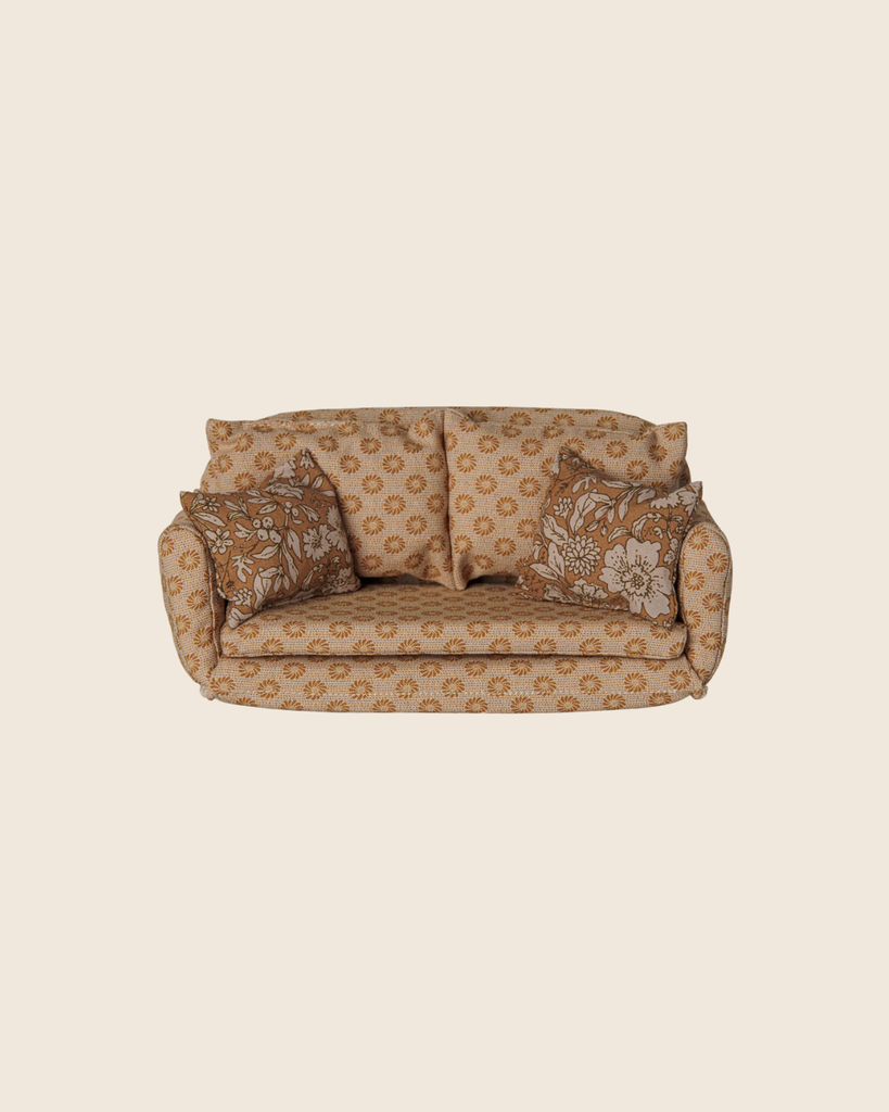 Miniature two-seat Maileg Christmas Tea With Grandma Set sofa with a small floral pattern and two square decorative pillows in a larger floral print.