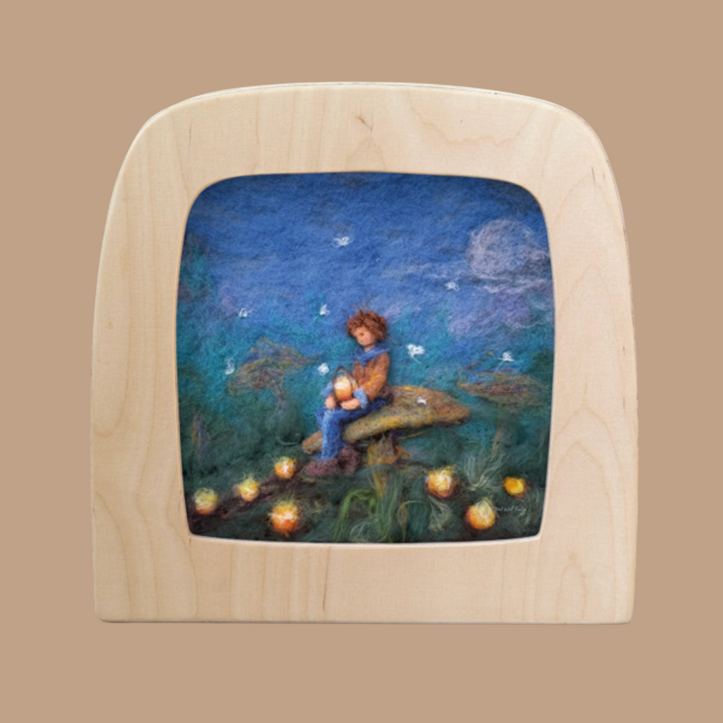 A child sits on a mushroom in a felt artwork, holding a glowing Toverlux lamp. Surrounded by magic silhouettes and twinkling lights, the night sky with a full moon adds to the unique atmosphere. This enchanting scene is framed in an elegant wooden arch. Product: Forest Lights for Toverlux Lamp.
