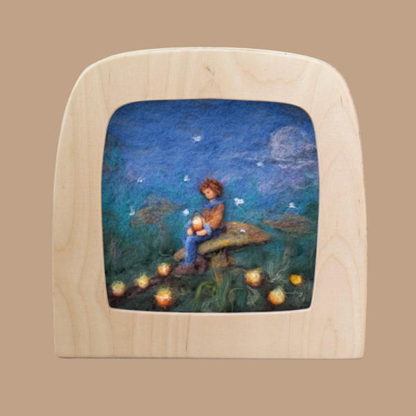 A child sits on a mushroom in a felt artwork, holding a glowing Toverlux lamp. Surrounded by magic silhouettes and twinkling lights, the night sky with a full moon adds to the unique atmosphere. This enchanting scene is framed in an elegant wooden arch. Product: Forest Lights for Toverlux Lamp.