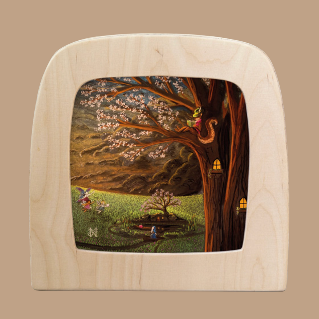 In the Silhouette Only - April for Toverlux Lamp illustration, a person with a tail sits on a flowering tree branch. Nearby, two figures dance beside a circular Toverlux mirror under a sky of magic silhouettes.