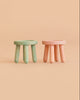 Two light green and light pink miniature wooden stools from the Maileg Garden Tea Set.